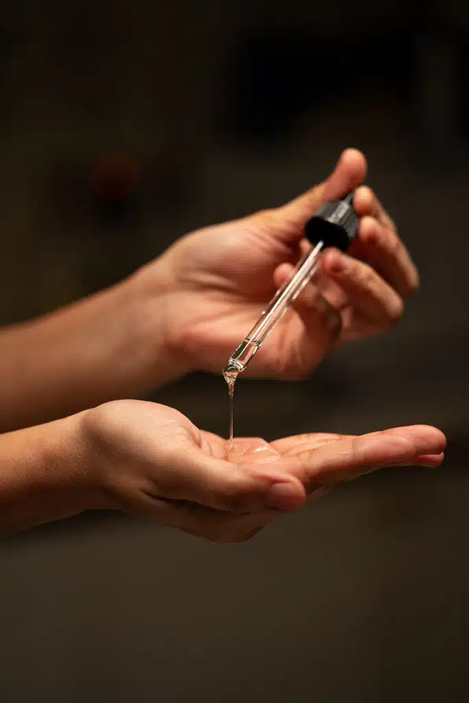 A practitioner's hands dispensing serum, composed like a study in artistry